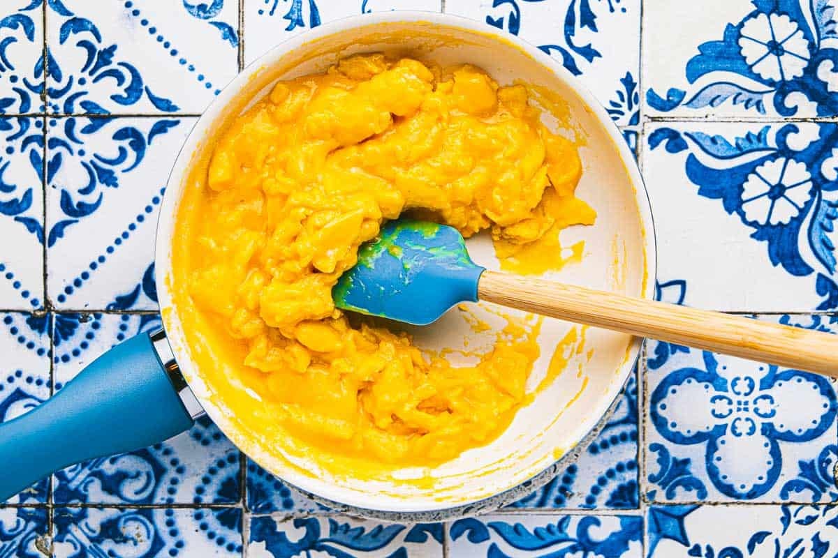 soft scrambled eggs being stirred with a spatula in a saucepan.