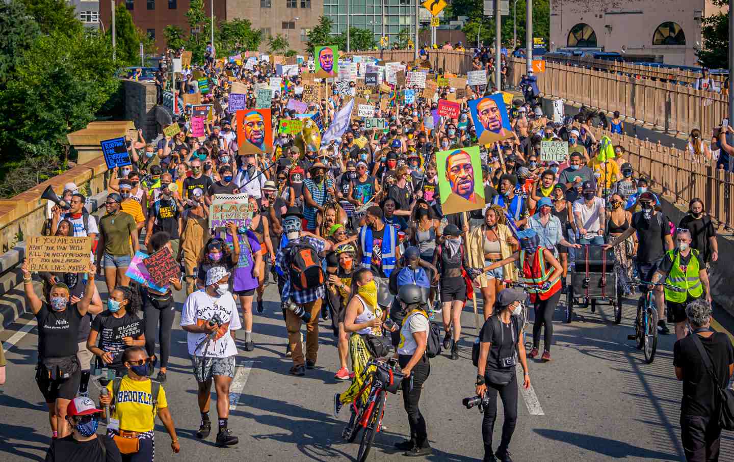 Marchers at a racial justice protest, with several holding up portraits of George Floyd.