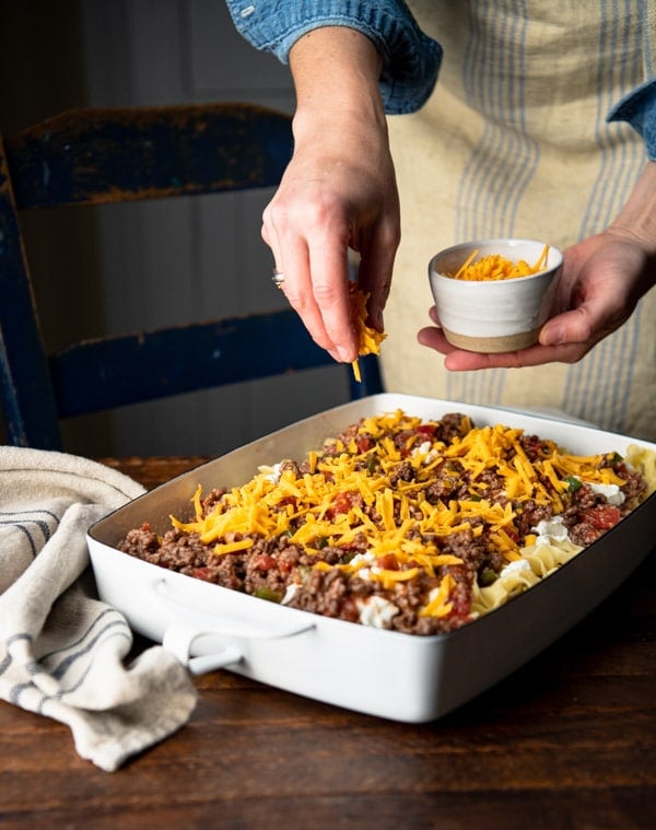 Sprinkling cheese on top of a casserole.