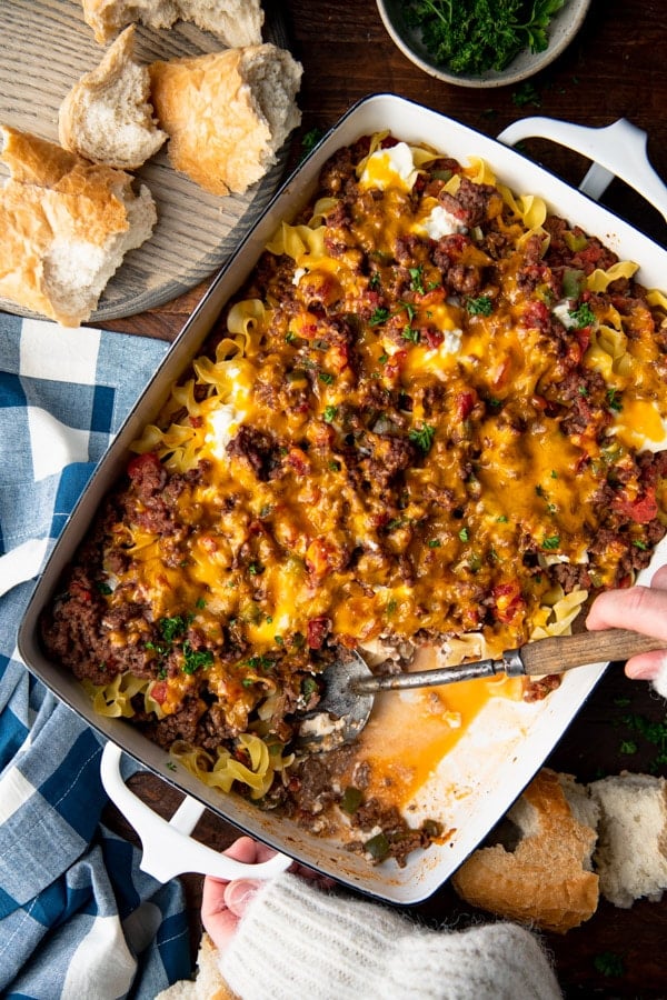 Serving spoon in a dish of hamburger noodle casserole.