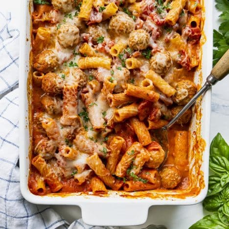 Square overhead shot of dump and bake creamy tomato pasta with turkey meatballs in a white baking dish.