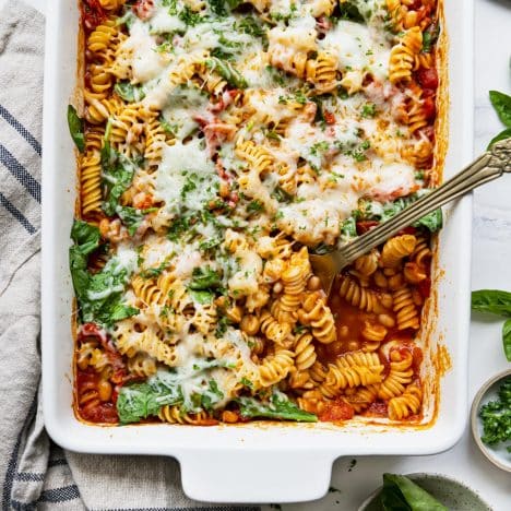 Square overhead shot of dump and bake white bean pasta with spinach in a white baking dish.