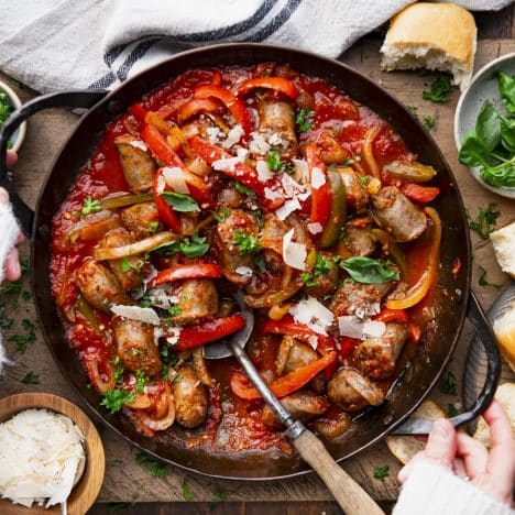 Square overhead shot of hands holding a pan of old fashioned Italian sausage and peppers.