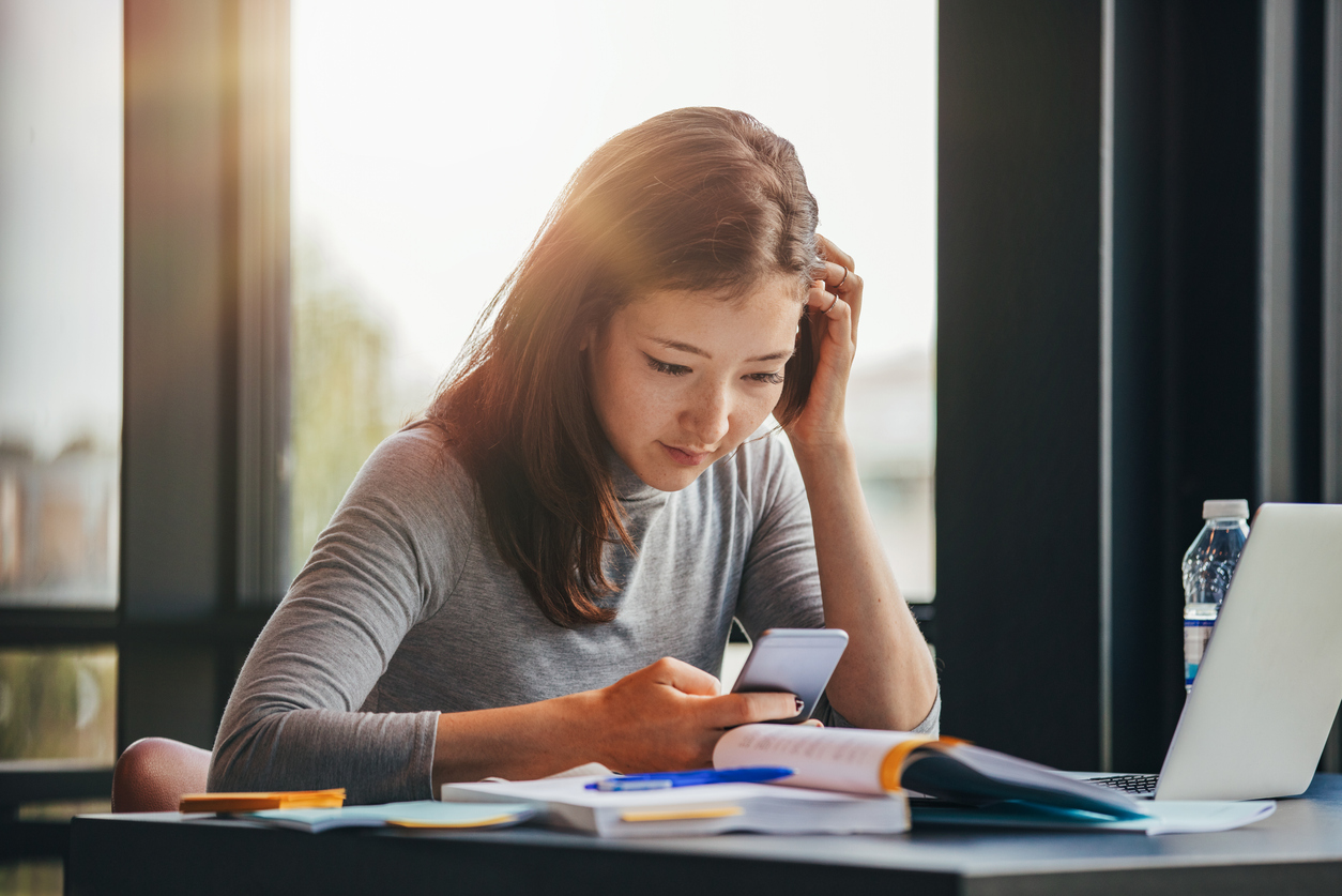 Student checks phone while studying