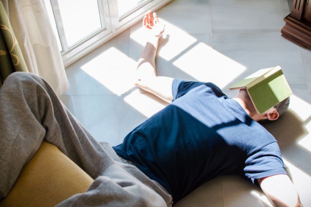 Young man resting on the floor with a book on his face