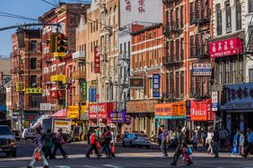 People walking and crossing the streets on Bowery in NYC's Chinatown 