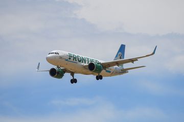 A Frontier Airlines airplane flying through clouds 