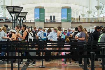 Travelers wait in line at a TSA security checkpoint at Denver International Airport 