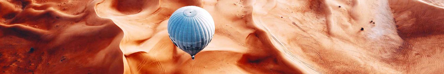 Blue hot air balloon over orange desert land