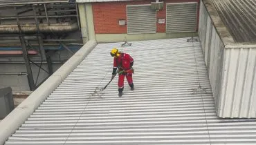 Trabalhador protegido enquanto realiza manutenção em uma estrutura elevada.