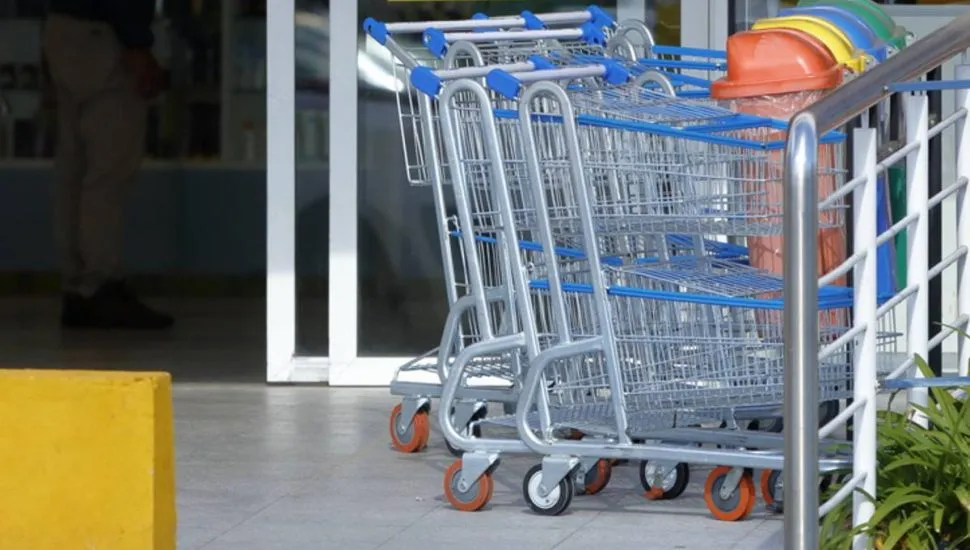 Imagem mostra um carrinho de compras em frente a um supermercado.