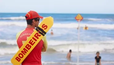 Na imagem, um bombeiro, de costas, monitora banhistas em praia do Paraná