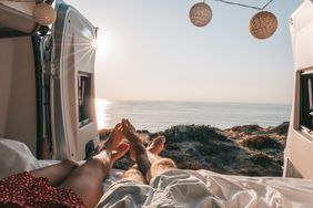 Couple lying at the back of a van looking at ocean, personal perspective