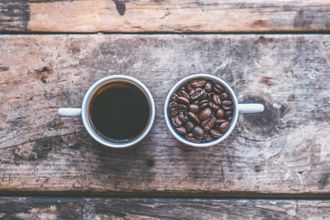 A cup of coffee next to a cup of coffee beans