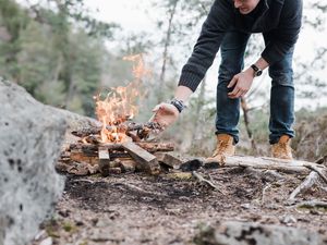 Man stacking firewood to build a campfire 