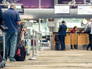 Passengers lined up at the airport to check in their luggage.