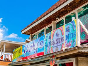 Colorful sign advertising a fish fry at Curly's restaurant in the bahamas with picture of beer on it.