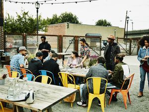 Group of friends hanging out at table at outdoor restaurant sharing drinks and food