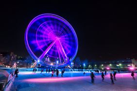 People enjoying the ice rink in front of Montreal's giant ferris wheel, Canada