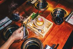 Hand pouring hot water from a kettle onto a bamboo steamer on a table with 4 individual burners