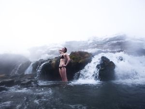 A beautiful woman standing in a hot springs waterfall in Montana.