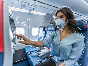 A woman flying on delta with a mask, touching the screen. White lines illustrated all around her