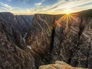 Sunsets over a deep canyon with a river running through it