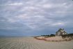 A grey shingle cottage sits on a dune overlooking a sandy beach in the Hamptons