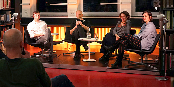 Zwei Männer und zwei Frauen sitzen auf einem Podium. 