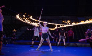 A person holds a spire in the air while flames surround them