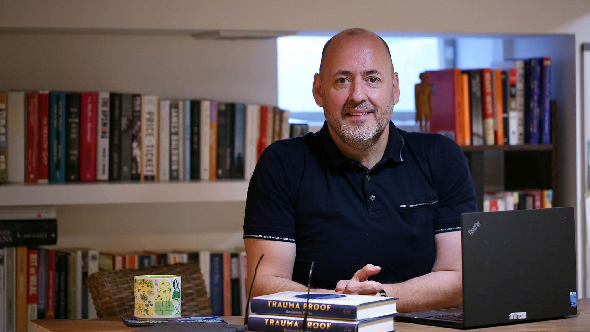 Benjamin Perks at his desk with copies of his book