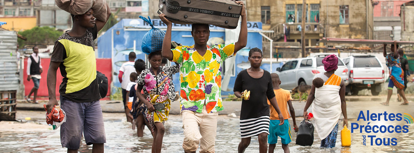 Des personnes marchent au milieu d'inondations en portant leurs affaires