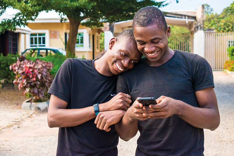 Deux hommes se tiennent par le bras en regardant un téléphone portable