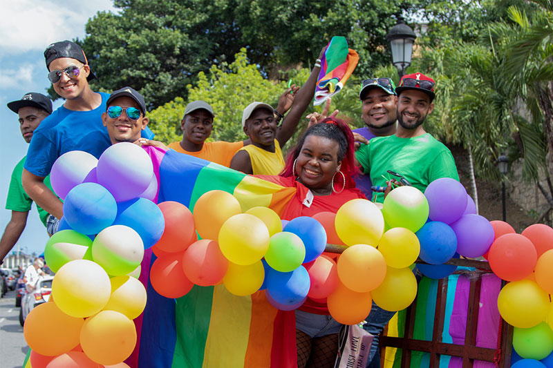 photo de personnes se tenant ensemble en plein air et tenant des ballons arc-en-ciel colorés et un drapeau arc-en-ciel