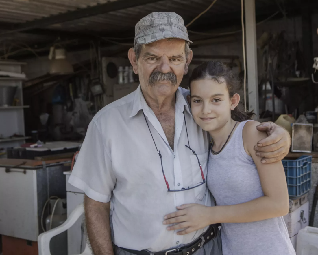 A farmer and his daughter standing in front of thier honey barn