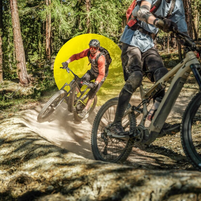 Zwei Downhill-Mountainbiker rasen eine Waldstrecke hinab