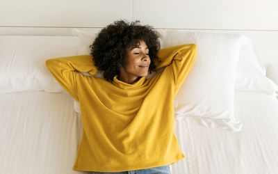 Smiling woman with closed eyes lying on bed