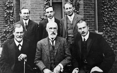six famous psychologists posing in front of college building