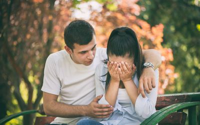 Man comforting woman on a bench