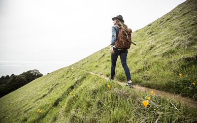 A woman with a backpack and hat on standing at a lookout