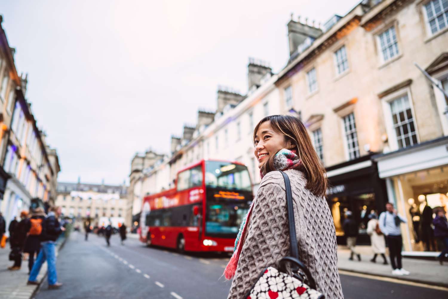 Cheerful Asian woman looking away while exploring in a town during travelling.