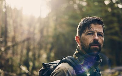 Contemplating, moody portrait of man in forest sunshine