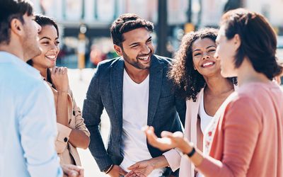 Group of smiling young people talking outdoors in the city