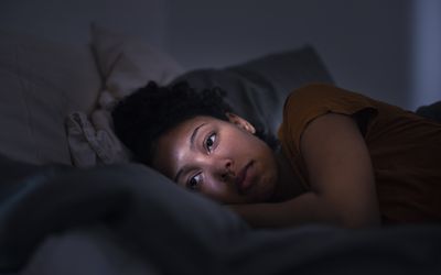 Pensive young woman lying in bed