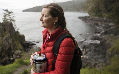 woman grieving while holding an urn by the water