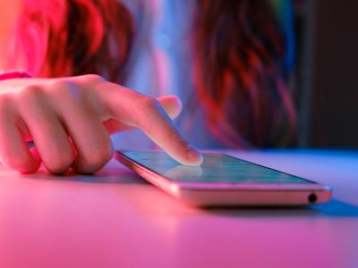 close up of teen girl with finger on iphone amidst pink and blue lighting