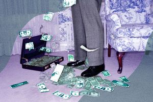 Dollar bills spread out across the floor and in a suitcase