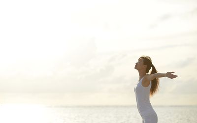 woman standing next to ocean with arms open