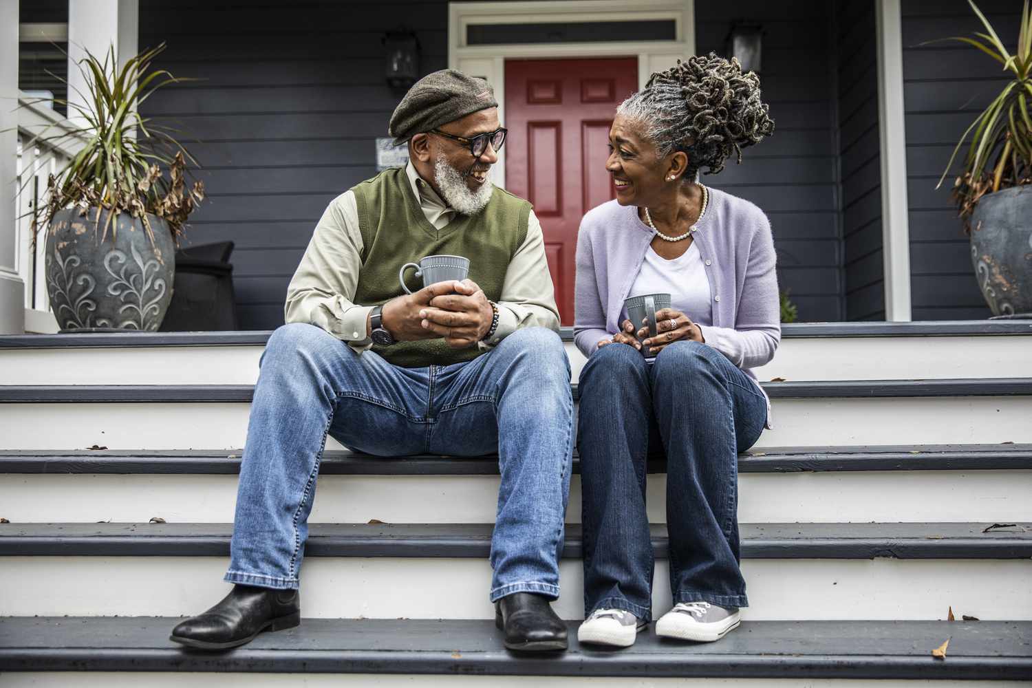 Senior couple having coffee in front of suburban home