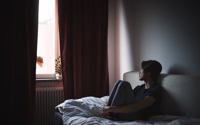 Pensive man sitting on sofa and looking through window